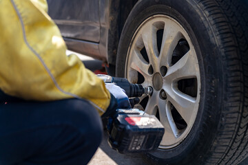 Professional Mechanic Changing a Tire with Power Tools in Bright Daylight