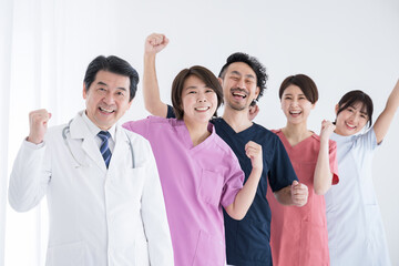 ドクターや看護師の楽しそうな転職成功などにガッツポーズのカメラ目線　横並びの医療従事者のイメージ　幅ひろい年齢で楽しそうな職場