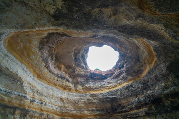 A breathtaking view of the skylight in Benagil Cave, showcasing the natural rock formations and the blue sky above. This famous sea cave is known for its unique beauty. Algarve, Portugal.