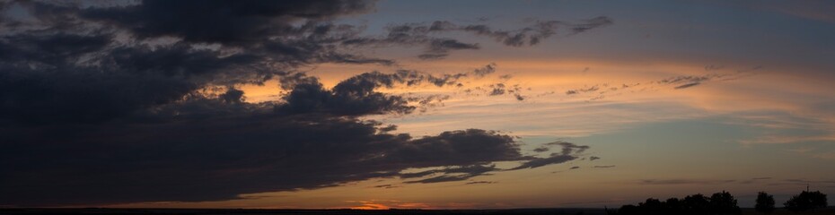 Landscape at sunset. Tragic gloomy sky. Panorama. Crimson twilight. Heavy, gloomy, dark clouds.