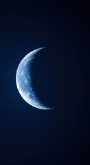 A crescent moon shines brightly in the dark night sky