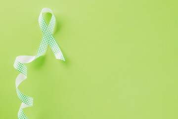 Green awareness ribbon symbol of Gallbladder and Bile Duct Cancer month isolated on green background with copy space, concept of medical and health care support, Cancer awareness, World bipolar day