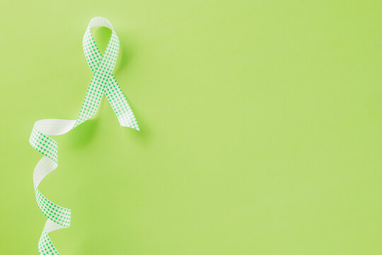 Green awareness ribbon symbol of Gallbladder and Bile Duct Cancer month isolated on green background with copy space, concept of medical and health care support, Cancer awareness, World bipolar day