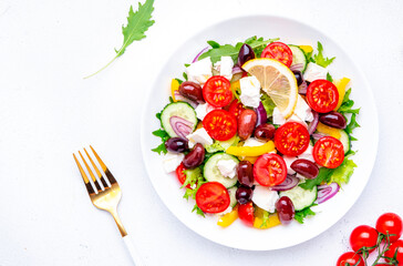 Mediterranean salad with vegetables, olives, cheese and lettuce, white background, top view