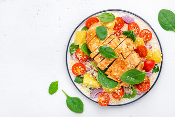 Nourishing salad with grilled chicken, couscous, tomatoes, onion, spinach and orange. White background, top view