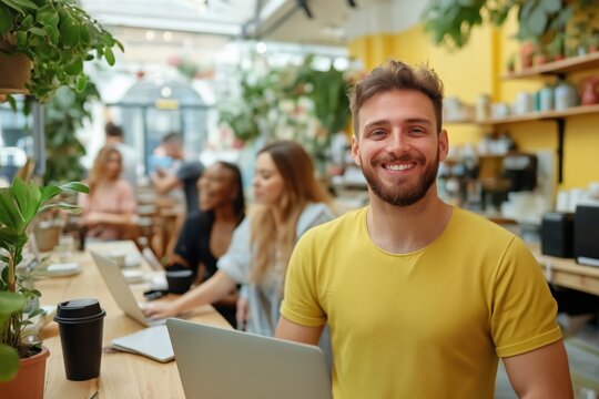 Freelancer smiling in a coworking space holding a laptop with business people working in the background - Powered by Adobe