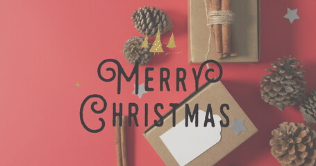 Image of merry christmas text banner over christmas decorations on red background