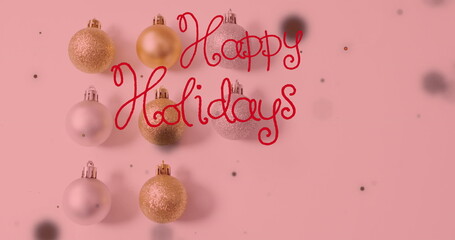 Image of happy holidays text over christmas baubles