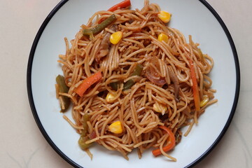 Chow mein or vegetable Hakka Noodles is a popular Indo-Chinese dish, served in plate, noodles stir fry with mushroom, sweet corn, vegetbales with sauce 