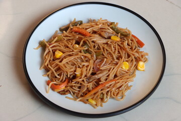 Chow mein or vegetable Hakka Noodles is a popular Indo-Chinese dish, served in plate, noodles stir fry with mushroom, sweet corn, vegetbales with sauce 