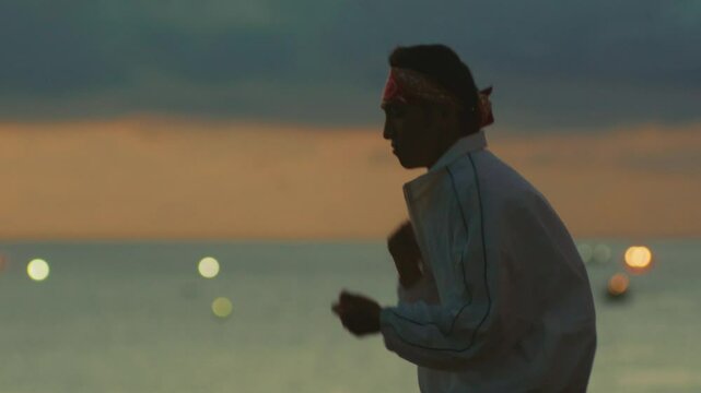 Man trains boxing by the ocean at sunset, filled with focus and energy