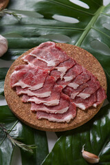 fresh raw pork shank sliced for shabu on a wooden plate