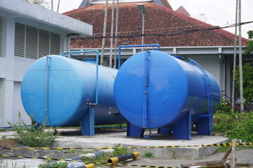 A large blue water tower on a building with bushes