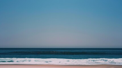 Fototapeta premium A serene beach scene with gentle waves and a clear blue sky.