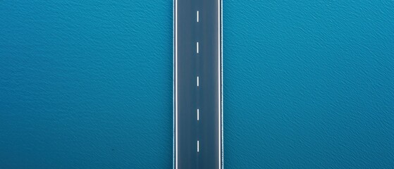 Fototapeta premium coastal highway freedom concept. Aerial view of a road stretching over blue water.