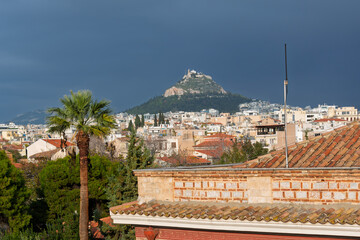 Obraz premium View of Mount Lycabettus and the historic downton of Athens, Greece, under dark stormy skies.