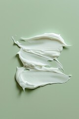 Obraz premium Creamy white substance smeared artistically on a soft green surface conveying a sense of freshness and simplicity