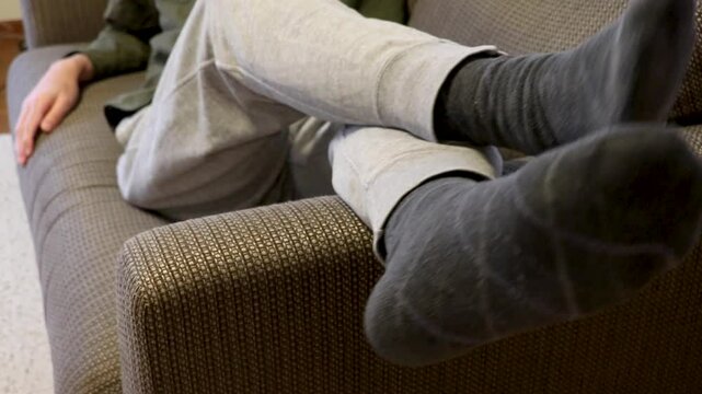 肘掛けに足を上げてソファーに横たわる男性