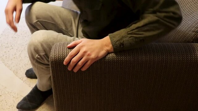 落ち着きなくソファーに座る男性