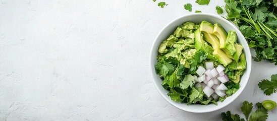 Obraz premium Fresh guacamole bowl with avocado cilantro and onion on light background ideal for food blogs and culinary promotions