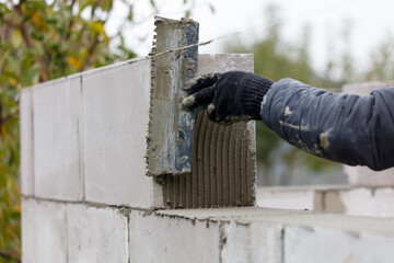A person is laying bricks and using a trowel to spread mortar