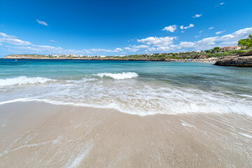 Obraz premium Azure Waters Lap Gently on Sandy Beach under Sun