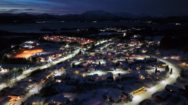 Aerial view of the snow-covered residential area of Storbakken at night on the island of Frei