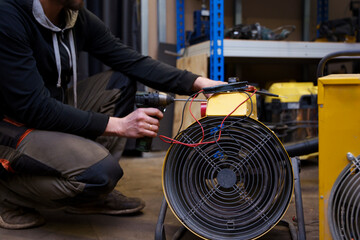 a male repairman repairs industrial electric heaters, he has a tool and a multimeter in his hands