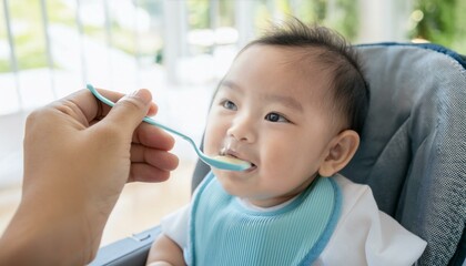 Hand feeds a smiling baby with a spoon, showing care and infant feeding.