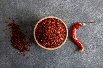 Red pepper flakes.Red chili peppers in wooden bowl on gray background.Dried chili peppers