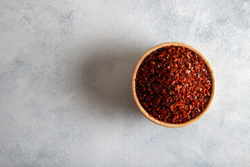 Ground red pepper flakes in a wooden bowl,top view

