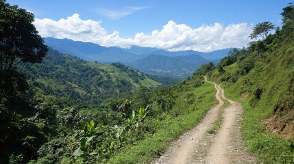 Scenic trekking route winding through lush hills with mountains in the background under a bright blue sky and fluffy white clouds.