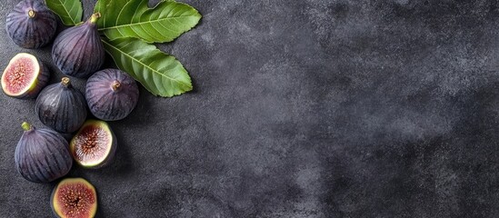 Fototapeta premium Fresh black figs with green leaves on dark textured background featuring blank space for customizable text or product description.