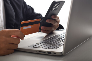 Close up of male hand holding credit card and smartphone, man paying online, using banking services, entering information, shopping, ordering in online store, making secure payment
