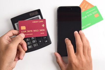 Man hand holding credit card and touch smartphone with calculator on table. Mobile payment, online shopping concept