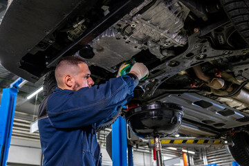 Auto mechanic drains old oil from car. view from bottom to top