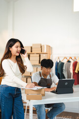 Young Asia businesswomen using mobile phone call receiving purchase order and check product on stock work at home office. Small business owner, online market delivery freelance concept.