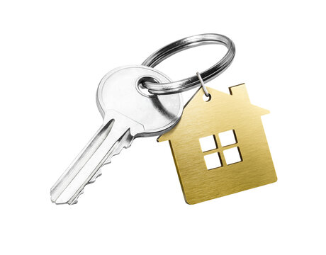 House key with golden house shaped keychain isolated on white background
