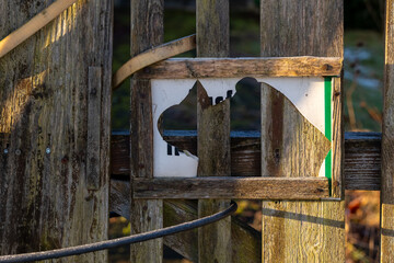 Weathered wooden fence with a broken sign revealing a hidden message in a rural setting at sunset
