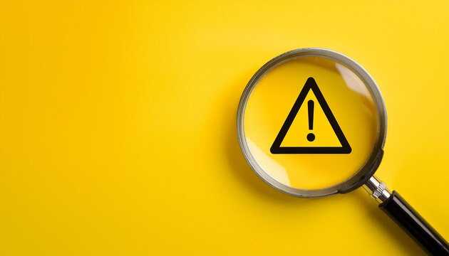Warning triangle sign and magnifying glass on a yellow background. Close-up.