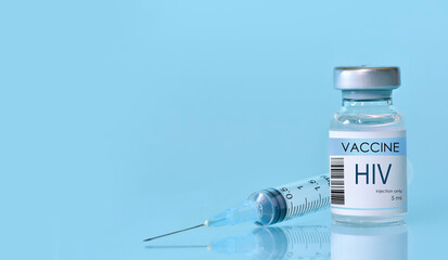 HIV Vaccine in a bottle with a syringe on a blue background. Experimental HIV vaccine vial for immunization against HIV disease. Copy space