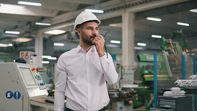 Talking by a walkie talkie. Man is working in the modern factory.
