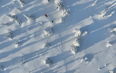 Aerial view of ski touring man and woman with snow shoes crossing winter mountains, fresh snow.