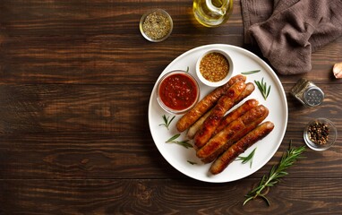 Plate with delicious grilled thin sausages on brown wooden background