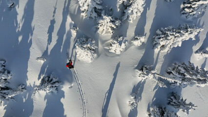Aerial view of ski touring man crossing winter mountains, fresh snow.