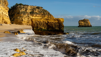 Dramatic Yellow Limestone Cliffs of Algarve with Scenic Coastal Landscape, Crashing Ocean Waves, and Smooth Sandy Beach, A Popular Destination for Tourists and Nature Enthusiasts