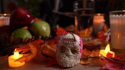 Sugar candy skull offering with Day of Dead decorations and candles.