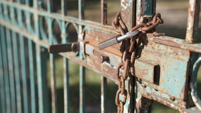 Old rusty iron gate closed with padlock and chain