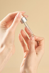 A woman applies nail care liquid to the skin with a pipette.