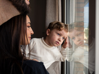 African mother and her mixed young son are looking out a window, observing the outside world. The...